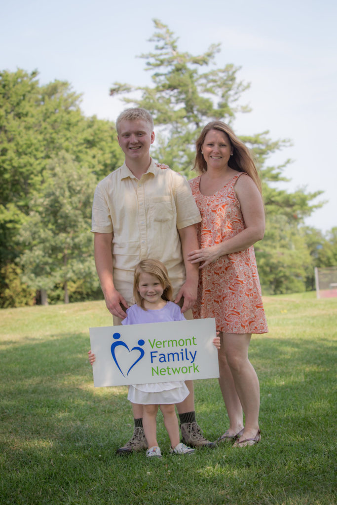 Mother standing next to son with young daughter in front holding a Vermont Family Network sign
