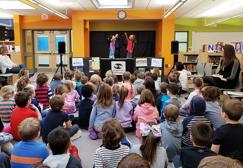 Puppet presentation with class with two puppets raising their hands