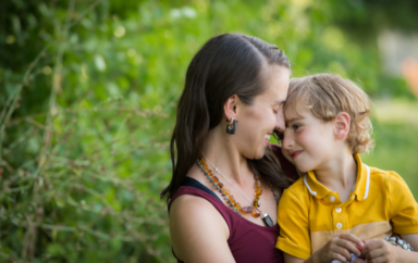 Smiling mother hugging son sitting in field son