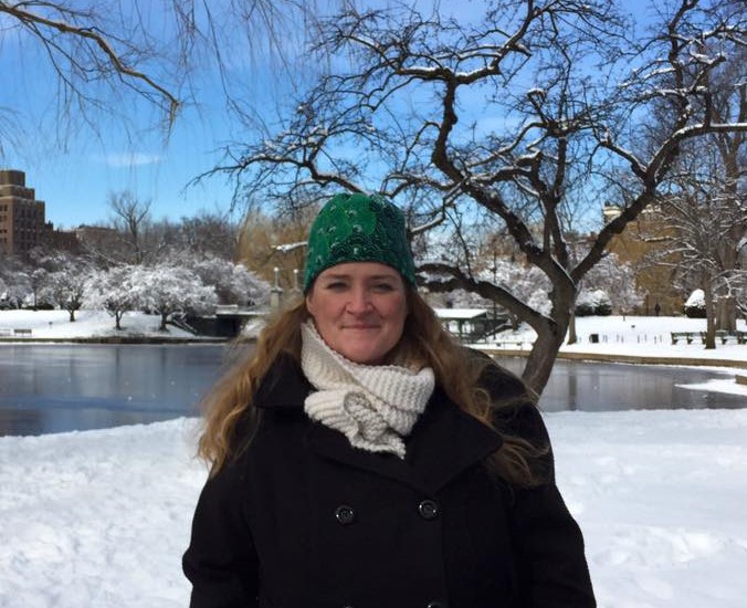 Dr.Jacqui Kellher wearing winter clothes stands in front of a snowy pond.